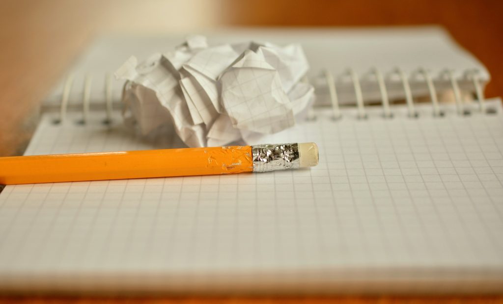 開かれたリングノートの上に、オレンジ色のエンピツ1本、くしゃくしゃに丸められた紙が置いてある