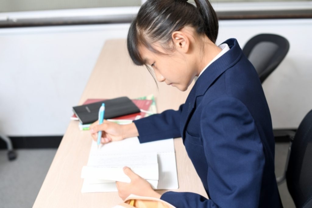 女子生徒が勉強をしている。水色のペンを持っている
